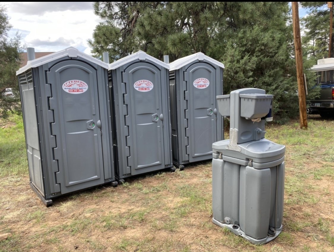 Atteberry portable toilets and a handwashing station set up among the pines